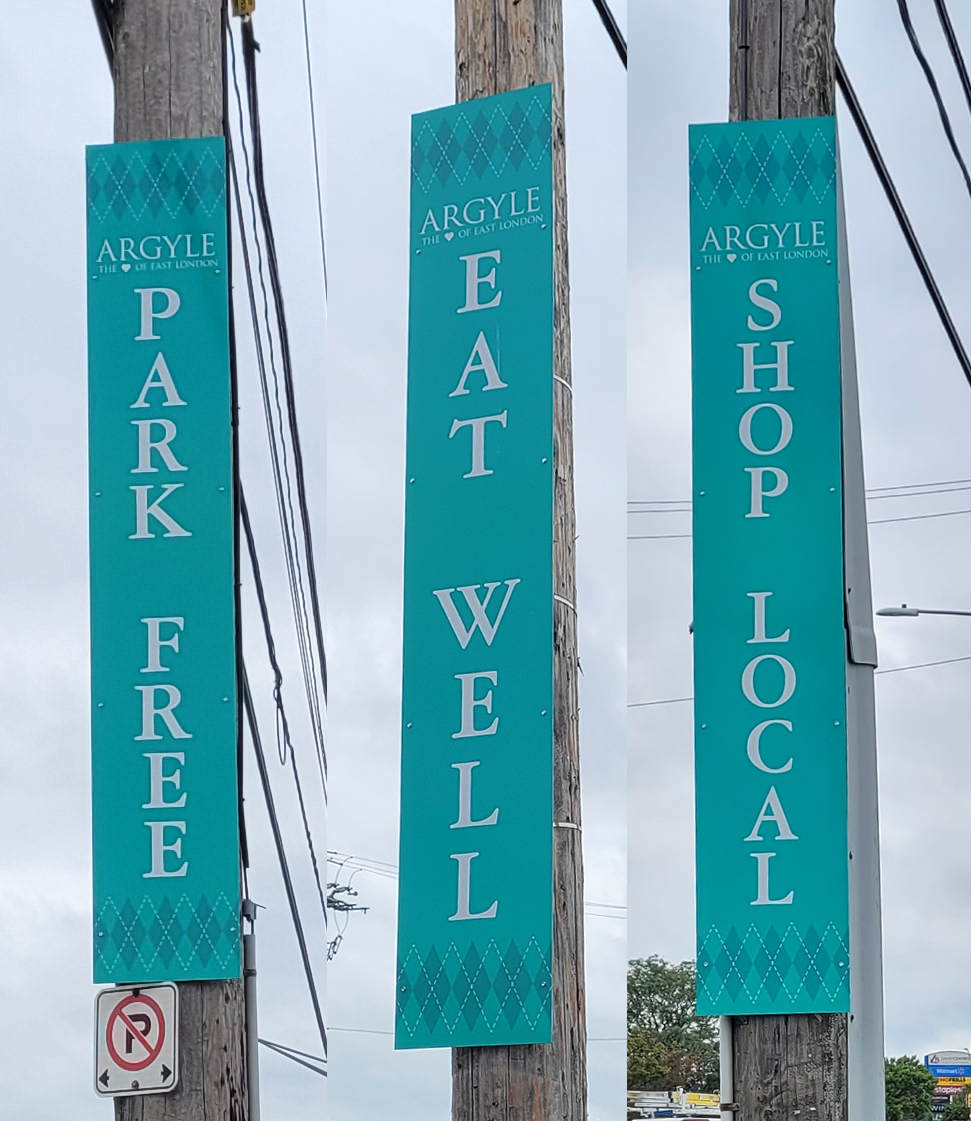 Signs affixed to 3 different telephone poles reading, "Park Free" "Eat well" and "Shop local"